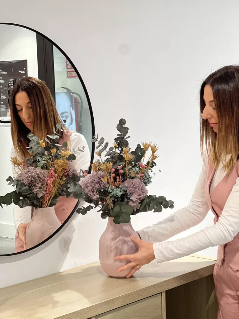 Mujer con jarrón con flores y reflejada en el espejo