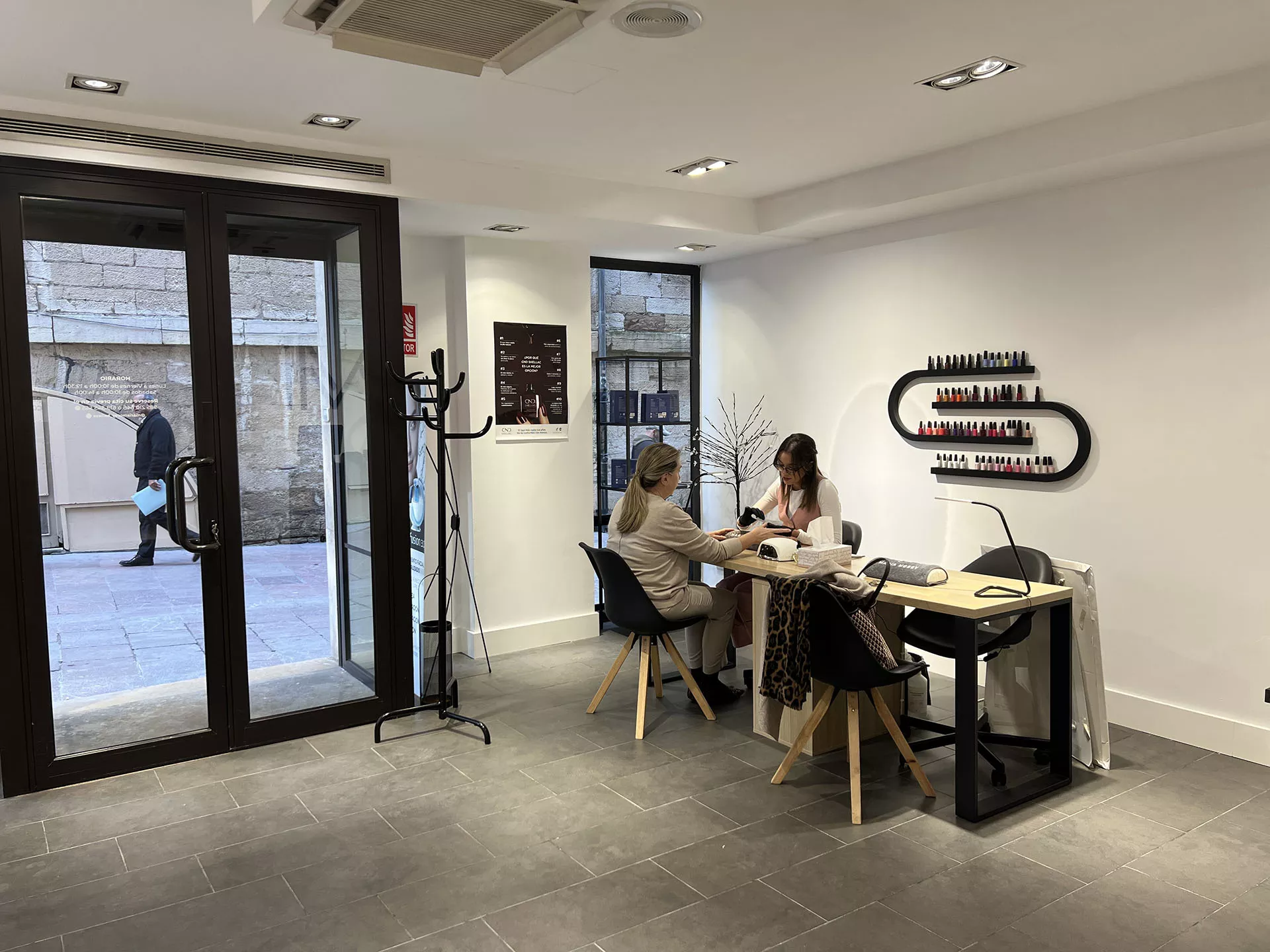 Mujer trabajando con una señora, ambas sentadas en el centro de estética con vista a la calle