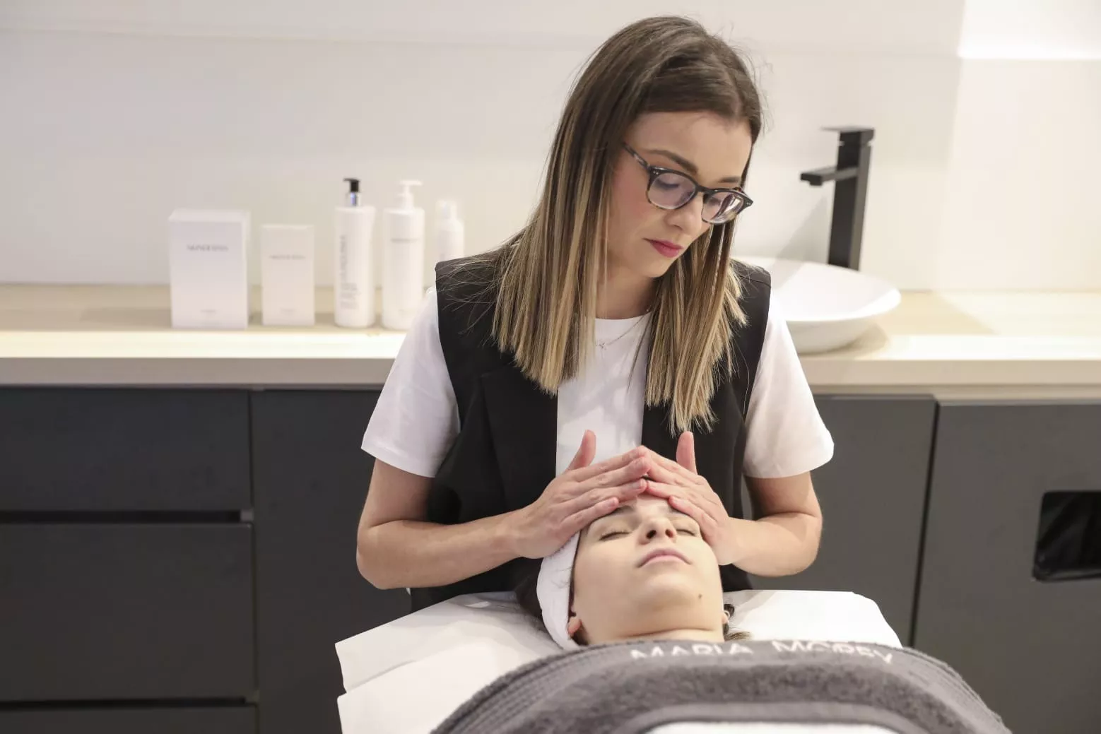 Mujer haciendo masaje facial a otra mujer en camilla