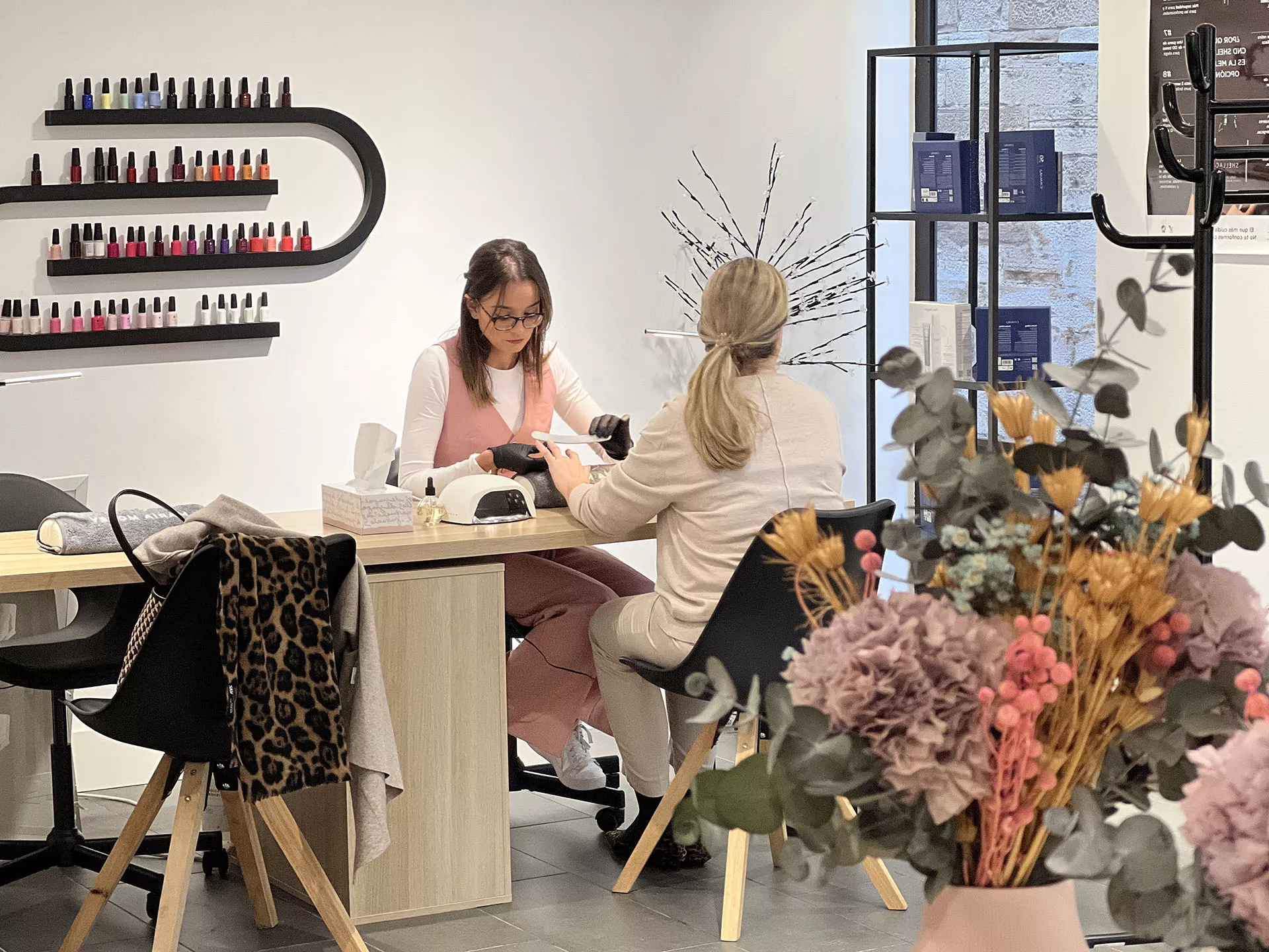 Mujer haciendo tratamiento a señora, ambas sentadas, decoración y productos